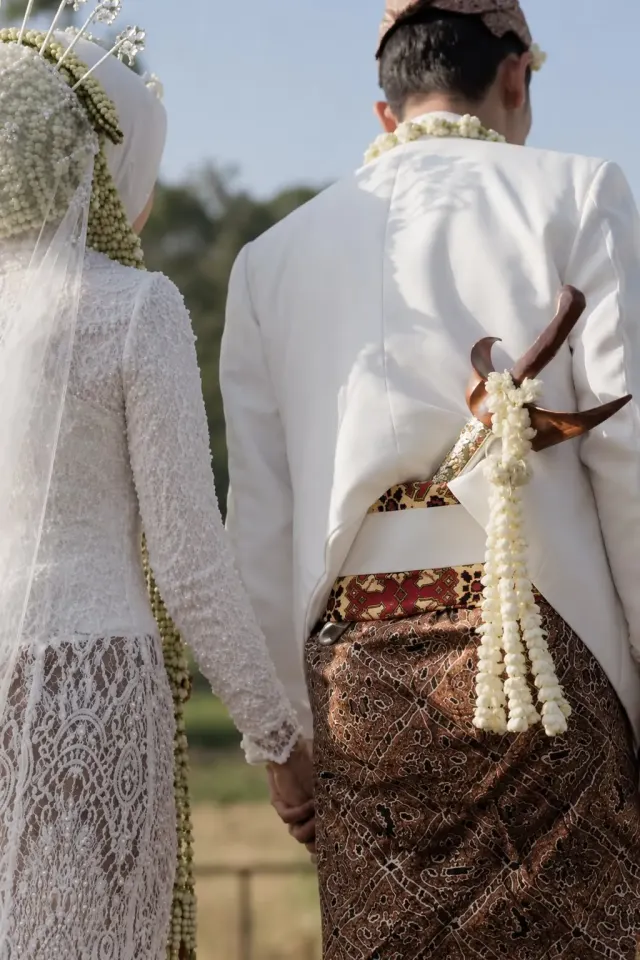 Bride and groom in traditional Javanese attire walking hand in hand